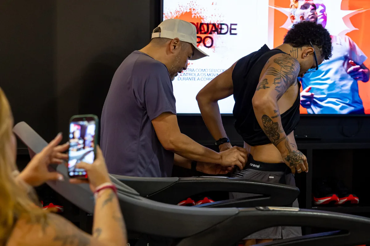 Profissional posiciona o sensor lombar para avaliação biomecânica da corrida.